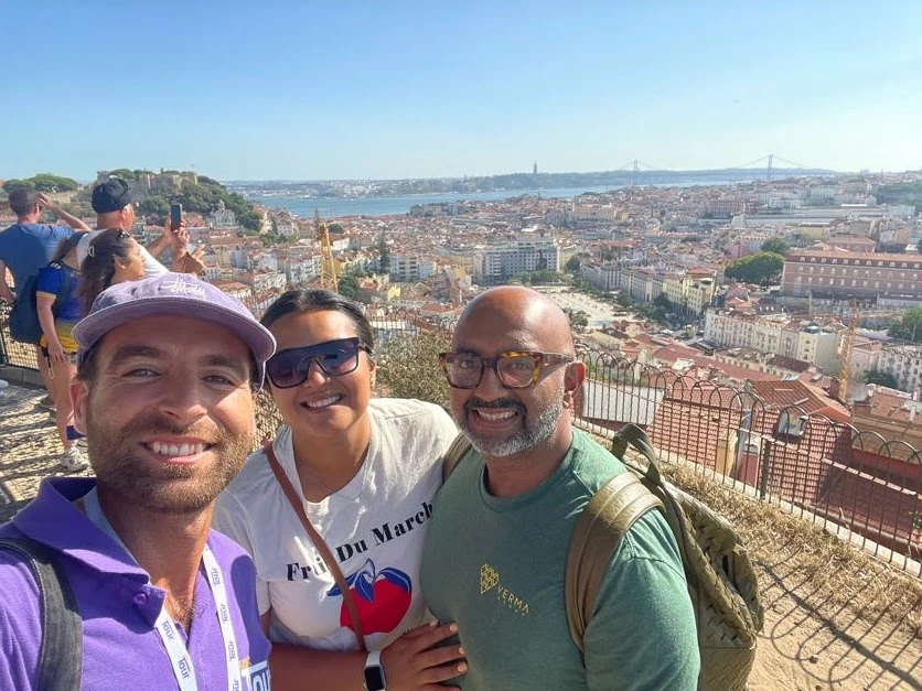 Just Tour It guide taking a selfie with happy guests at a panoramic viewpoint overlooking Lisbon, the Tagus River, and the 25 de Abril Bridge.